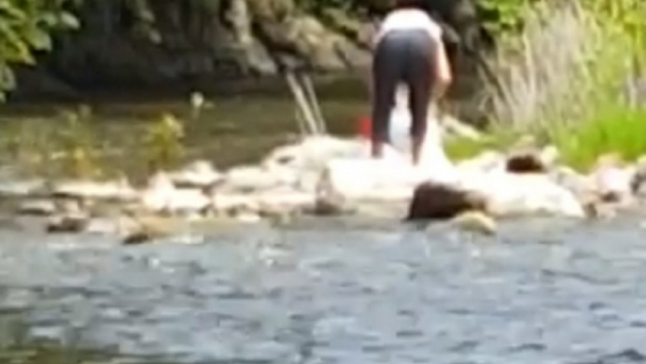 Žena baca smeće u reku