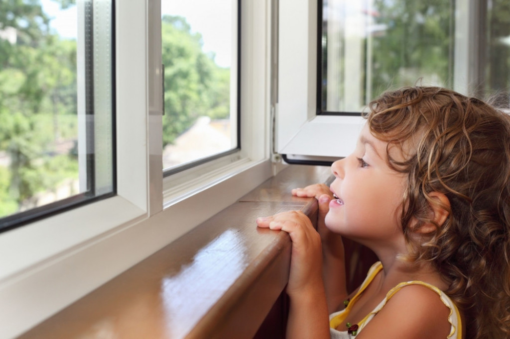Devojčica viri gleda kroz prozor