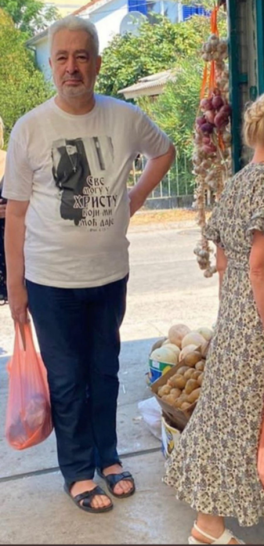 KRIVOKAPIĆ USLIKAN U BIJELOJ U papučama za plažu, čeka red u mesari, natpis na majici svima upada u oči