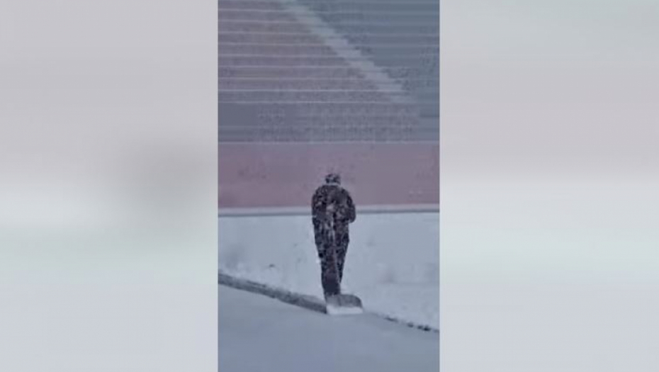 Trener čisti sneg na stadionu