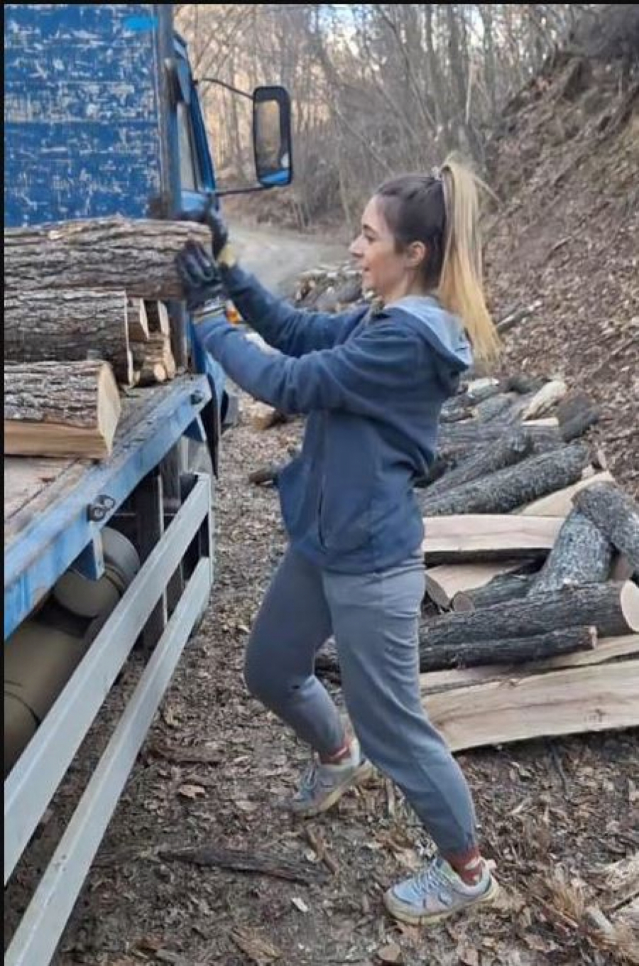 Devojka slaže drva na kamion
