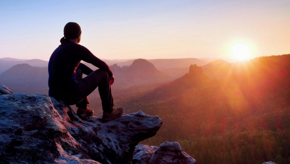 čovek sedi na kamenu