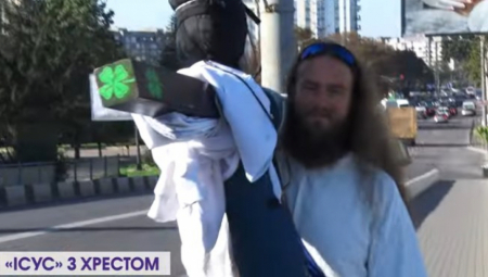 ZAPUTIO SE PEŠKE U KIJEV Momak obučen kao Isus nosi na leđima veliki drveni krst, a ima samo jednu poruku